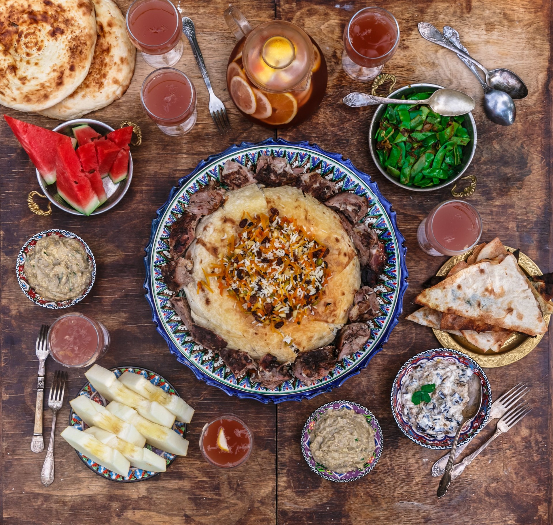 Pilaf with lamb in traditional plate with appetizers, top view flat lay