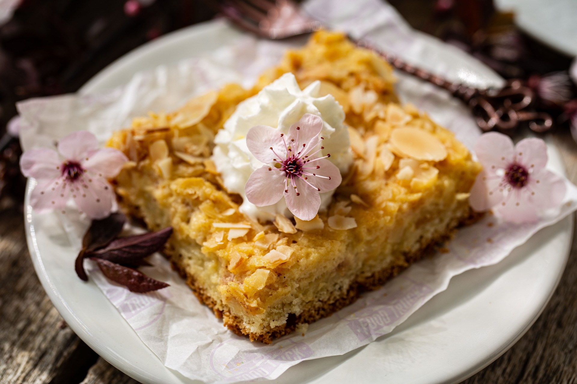 Piece of apple cake with almonds. Decorated with flowers.