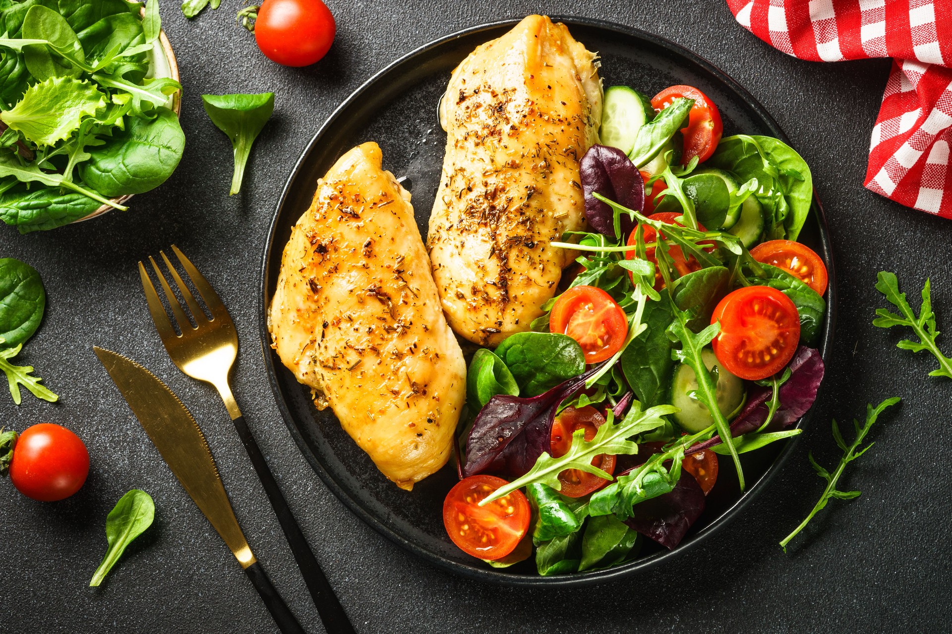 Green salad with chicken fillet on black.