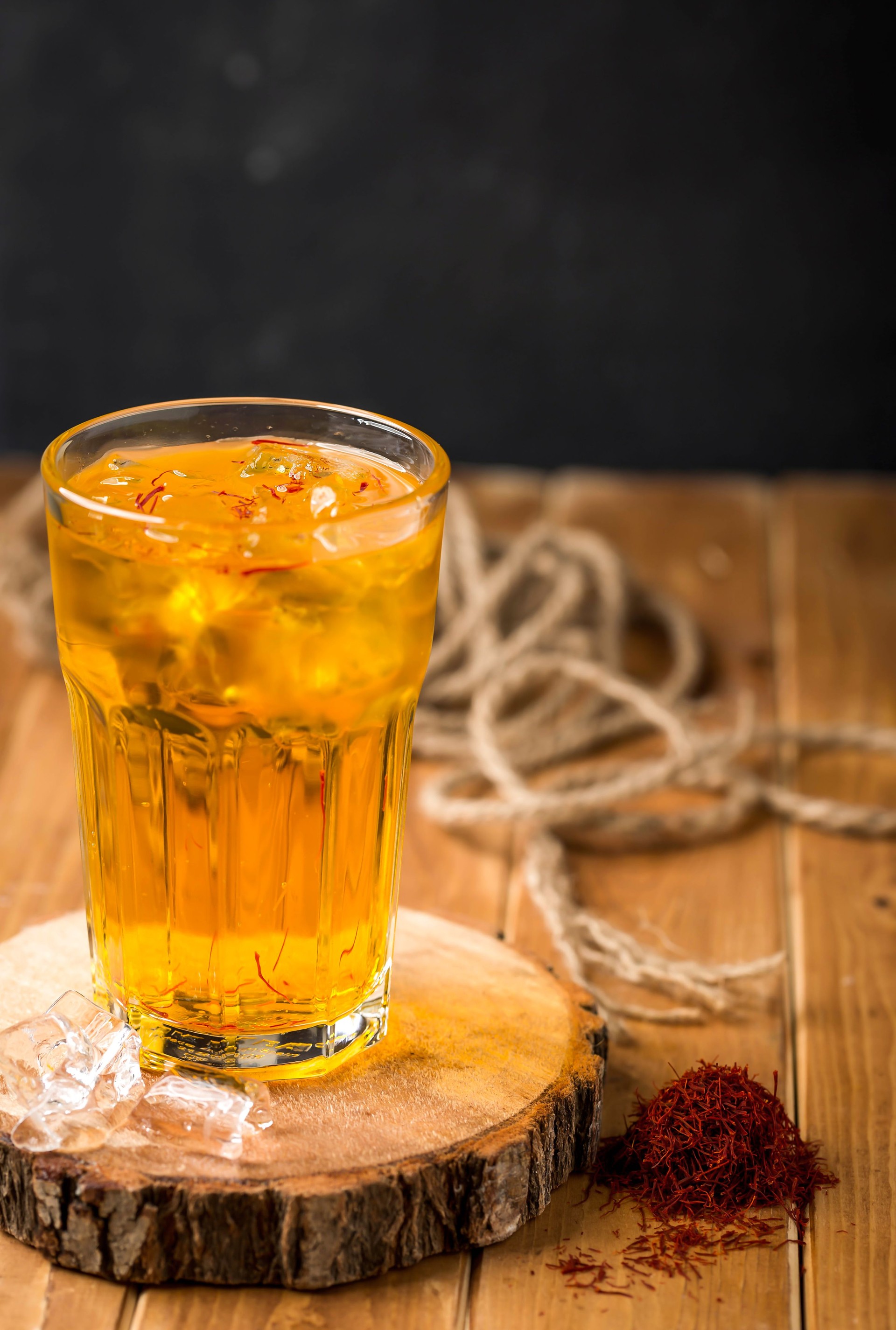 Saffron sharbet with ice cube served in glass isolated on wooden table side view of arabic drink